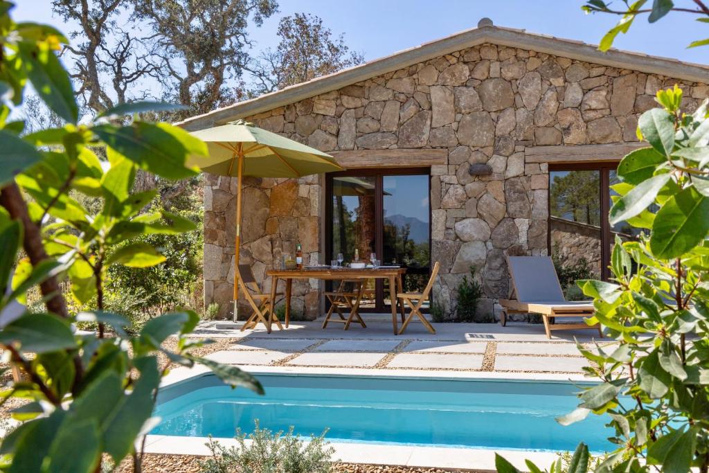 a cottage with a pool and a table and an umbrella at Hameau de Petripini in Sotta
