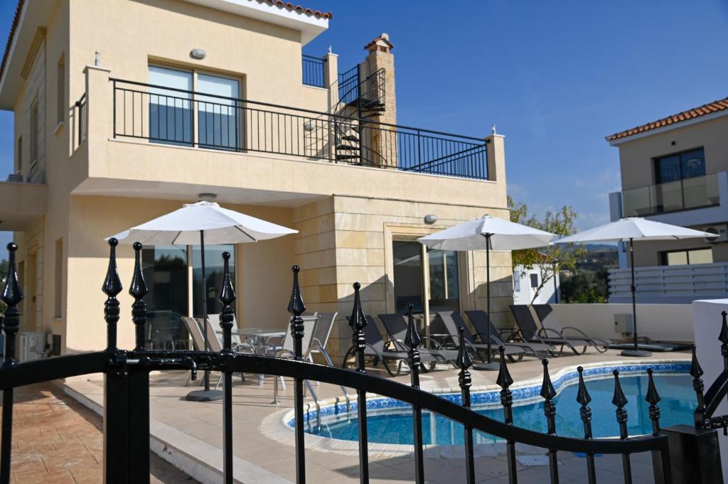 a pool with chairs and umbrellas next to a building at Sorelia Latchi Villas 1- Merope Irena in Polis Chrysochous