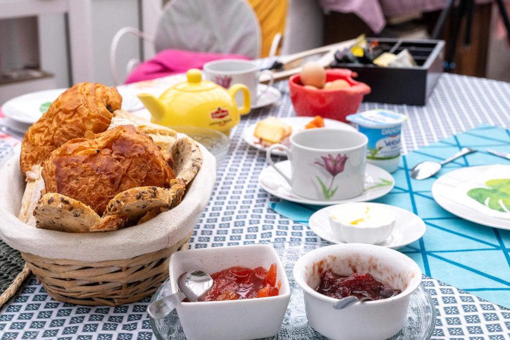 a table with a basket of food and cups on it at Chambres d'hôtes ''La Grand' Maison'' in Escalles