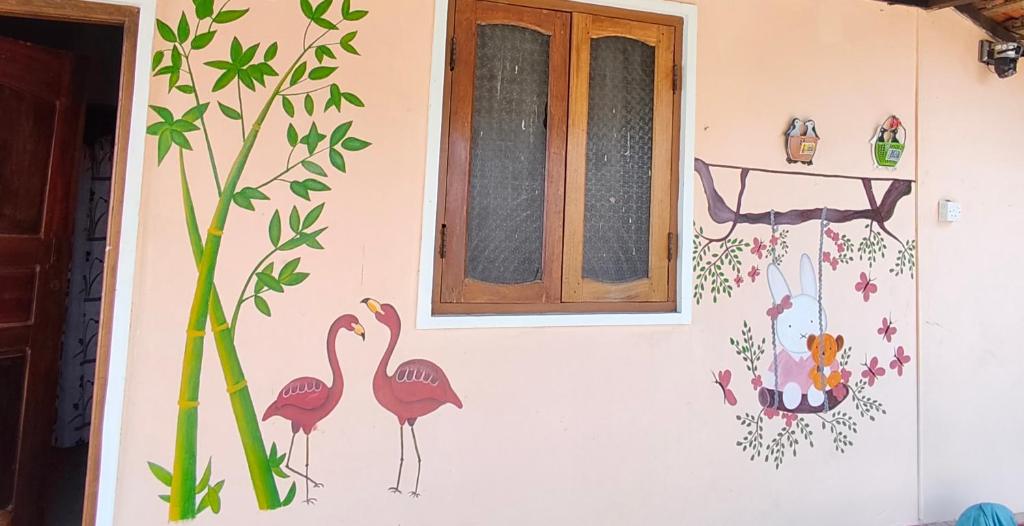 a wall with flamingos painted on the side of a house at S P Restaurant in Kallady