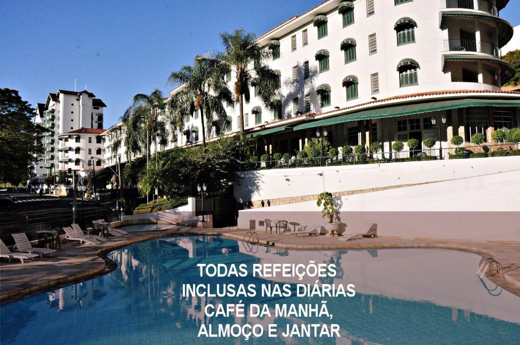 a sign in front of a building with a swimming pool at Hotel Monte Real in Águas de Lindoia