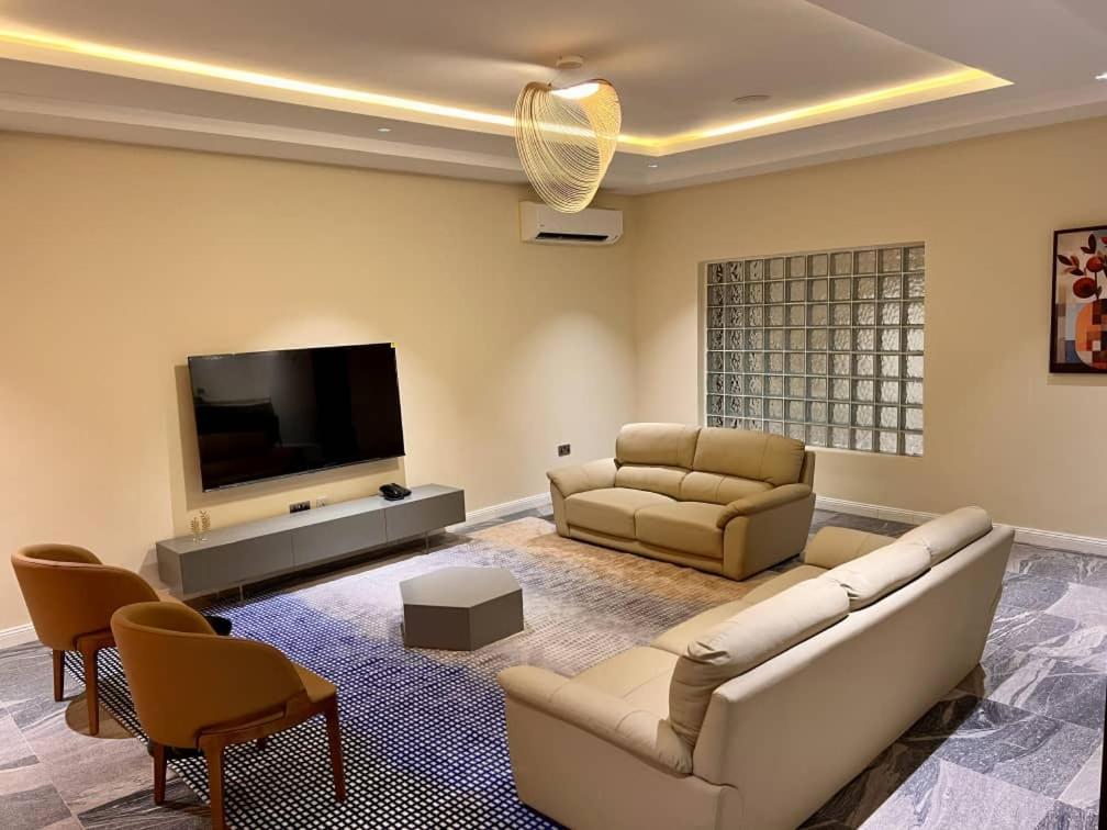 a living room with two couches and a flat screen tv at Saadatus Apartment in Kaduna