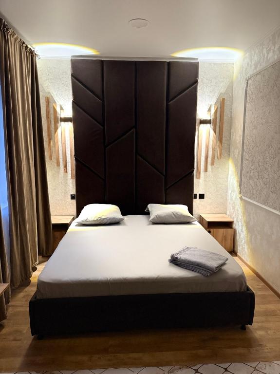 a bedroom with a large bed with a large headboard at Adel in Almaty