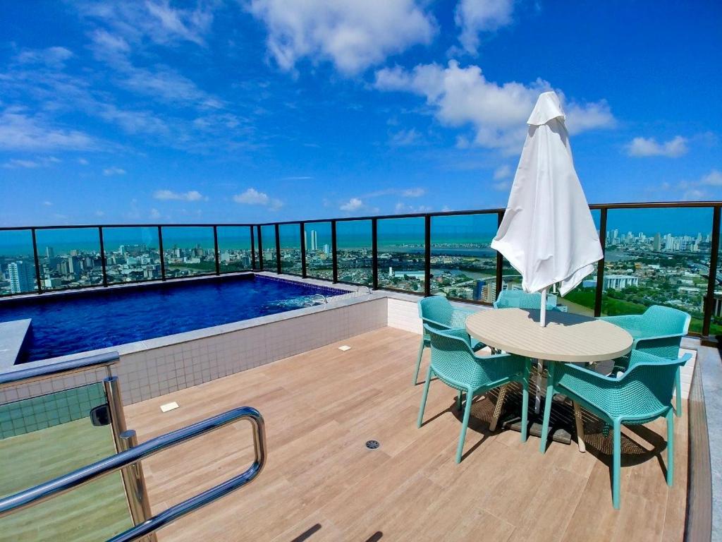a balcony with a table and chairs and an umbrella at Flat Ilha do Leite in Recife