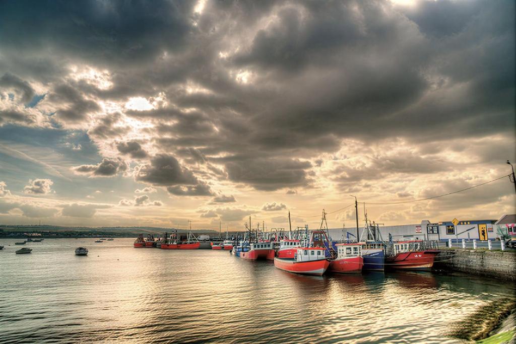 a group of boats docked in the water under a cloudy sky at The Captains Wheel in Skerries