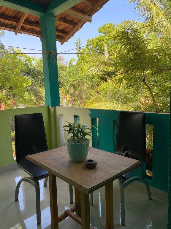 a table with two chairs and a potted plant on a porch at DEMITHA guest in Ranna