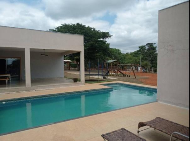 a swimming pool with a playground in the background at Sitio Vila Monte Verde in Jaboticatubas