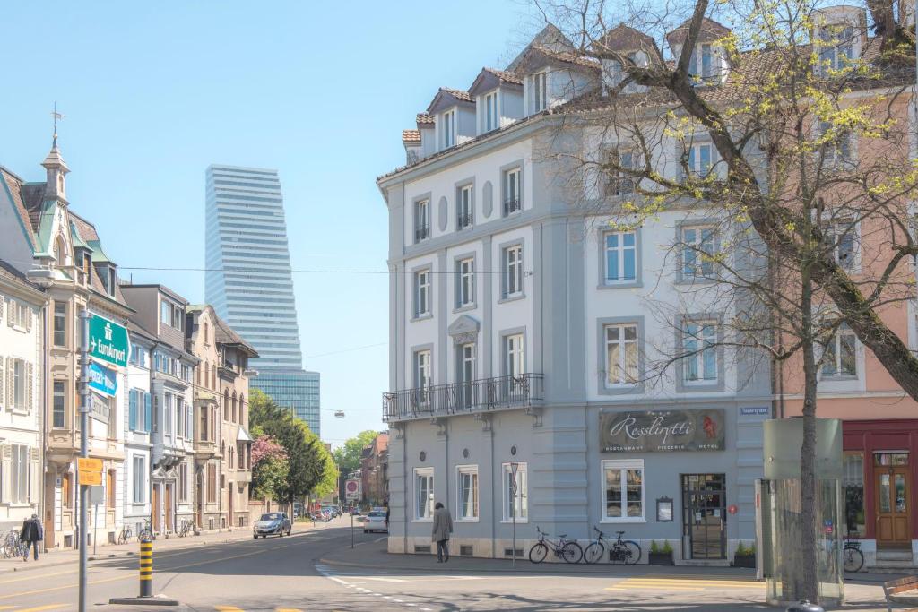 a tall white building on a city street at Hotel Restaurant Resslirytti in Basel