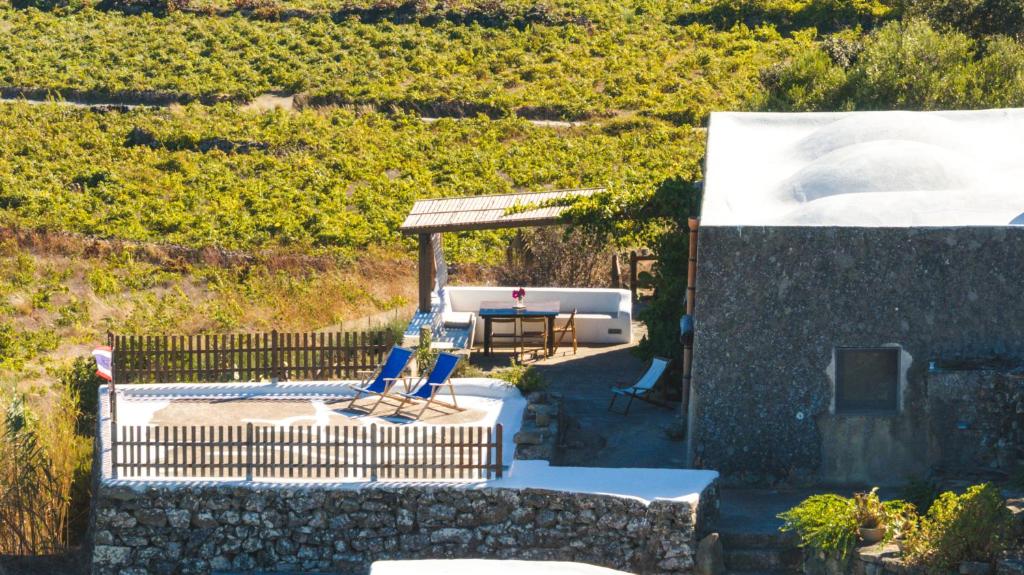 a patio with a table and two blue chairs at Dammuso del Nonno in Pantelleria