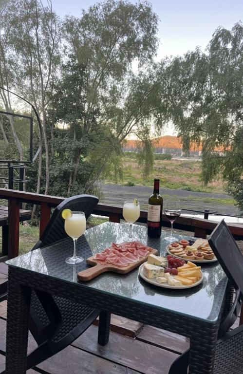 a picnic table with wine glasses and food on it at Alojamiento BordeRío in Concepción