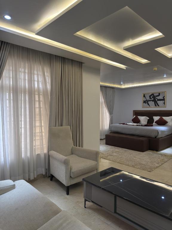 a bedroom with a bed and a couch and a chair at Glovis Suites in Abuja