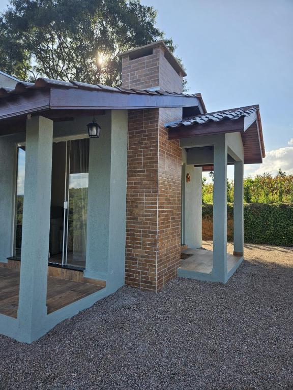 a brick house with two columns and a porch at Cabana Sol Poente PR in São José dos Pinhais