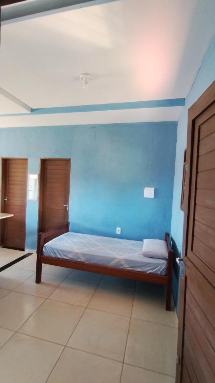 a bed in a room with a blue wall at Hostel Casa da Cida II in Pipa