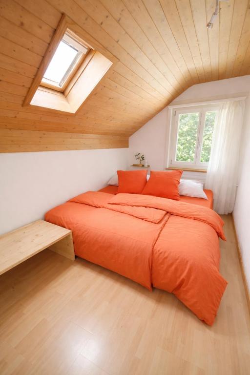 a bedroom with an orange bed in a attic at Quiet Forest-Side Apartment in Flamatt