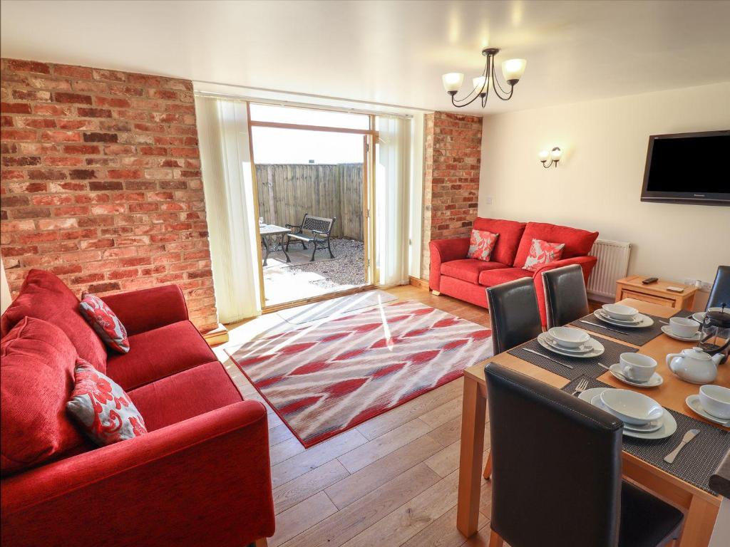 a living room with red furniture and a brick wall at The Granary in Louth