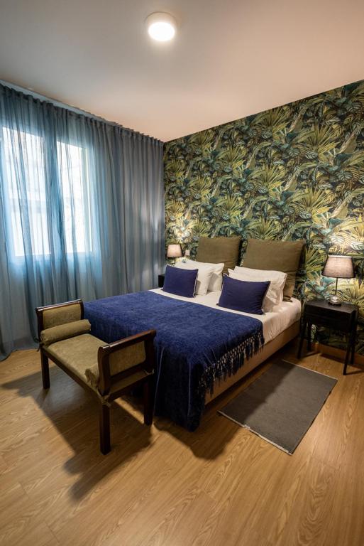 a bedroom with a blue bed and a chair at Queimada Houses in Funchal