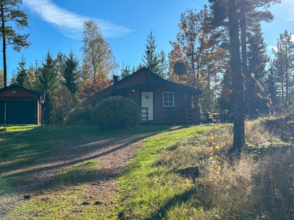 Eine Hütte im Wald mit einem unbefestigten Weg davor in der Unterkunft Farmstay Götes Cabin, 2p in Årjäng
