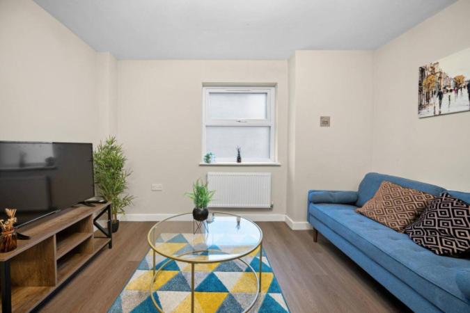 a living room with a blue couch and a glass table at 2BR Apartment in Cardiff’s Vibrant Roath in Cardiff
