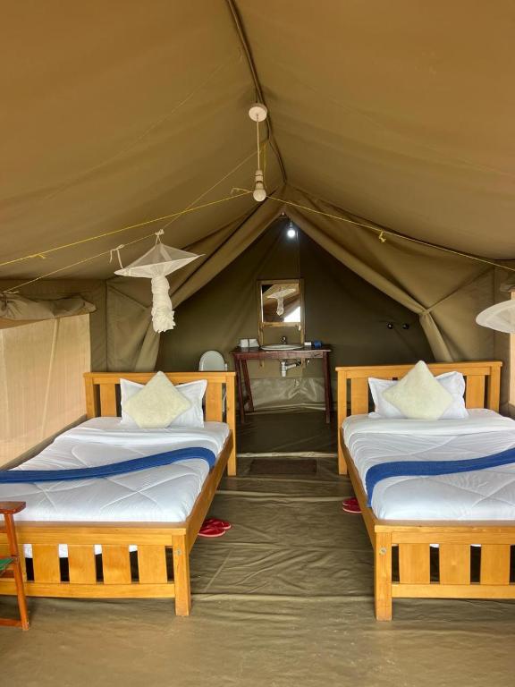 a bedroom with two beds in a tent at Mara Sunset Acacia Camp in Sekenani