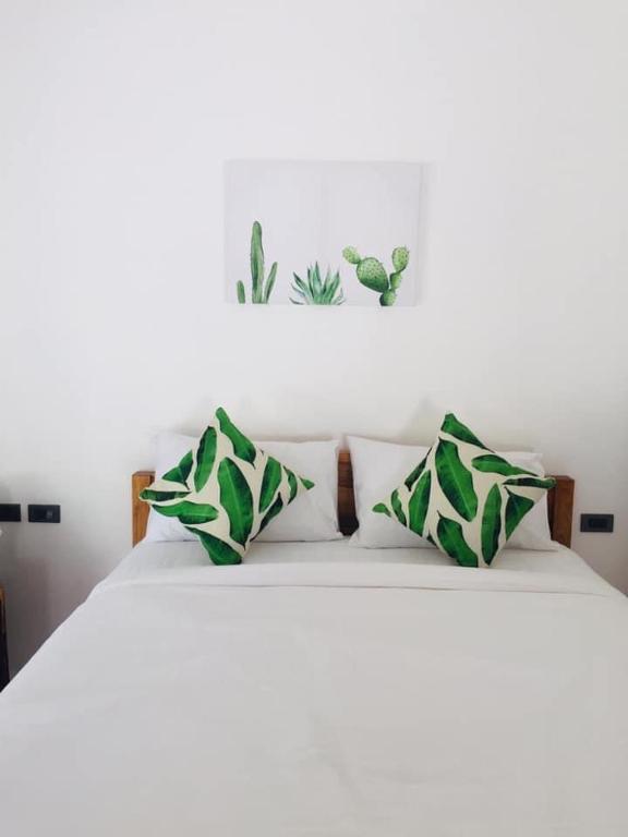 a white bed with green and white pillows on it at Sweet Room by Maliblue Khanom in Ban Phang Phrao