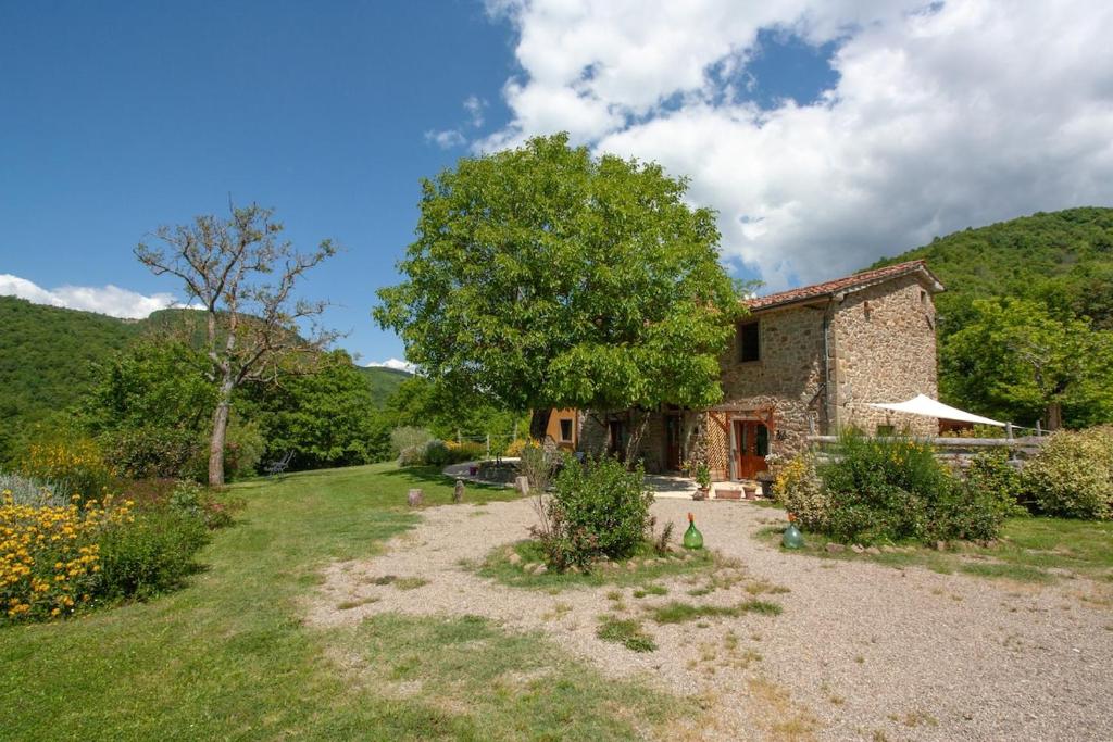 a stone house in the middle of a garden at Romantic stone farmhouse studios with private terrace in beautiful Tuscany in Subbiano