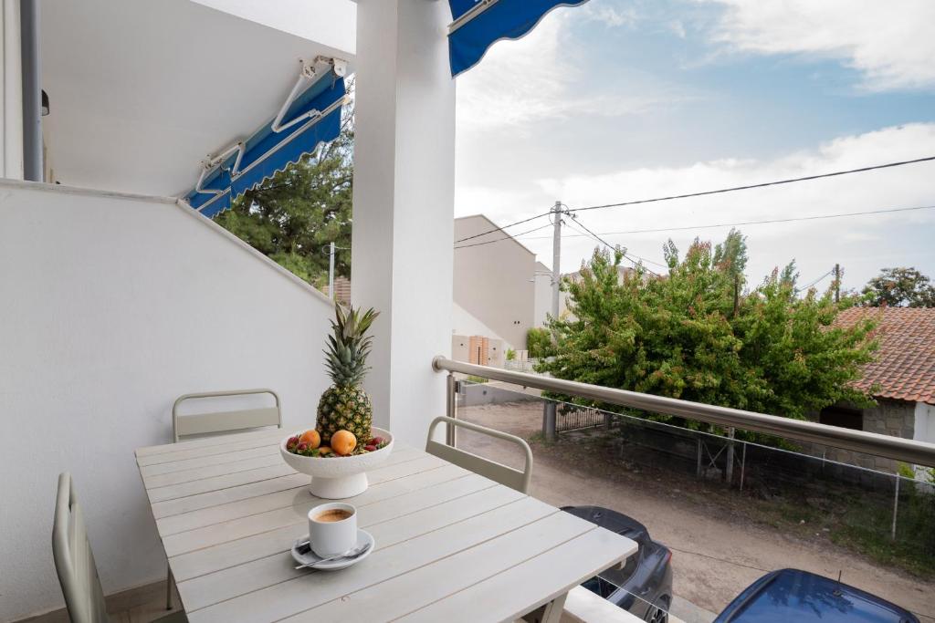 a table on a balcony with a cup of coffee and a pineapple at Azur Apartments by Paralia Living in Nikiti