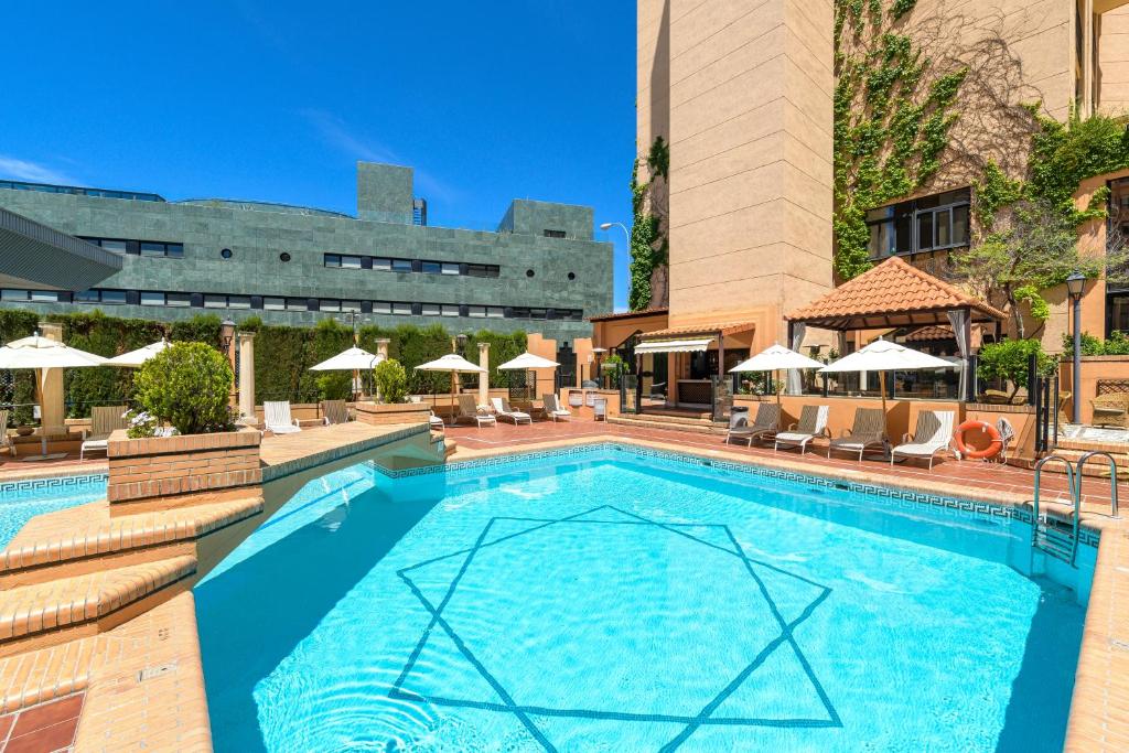 a swimming pool with chairs and umbrellas at a hotel at Hotel Saray in Granada