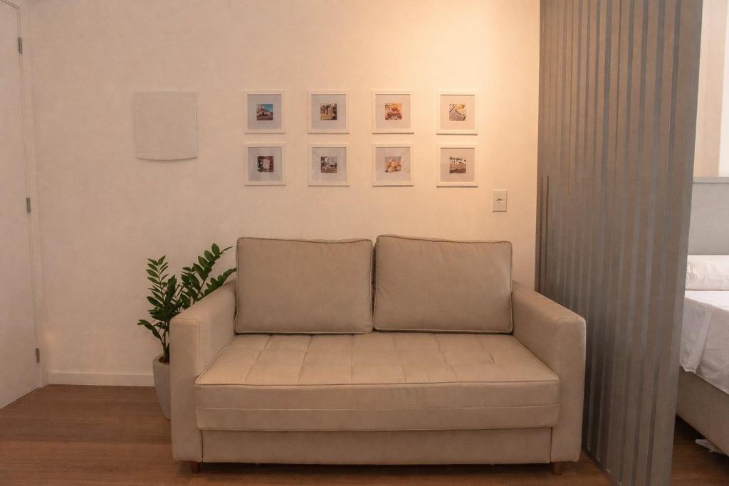 a couch in a living room with pictures on the wall at Flat 400m da UFV 650m da Rodoviária in Viçosa