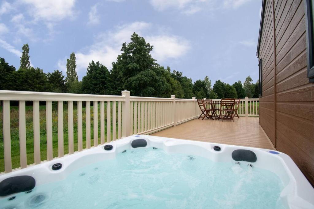 a hot tub on a deck with a fence at JJs Lodge Jorvik in Walkington