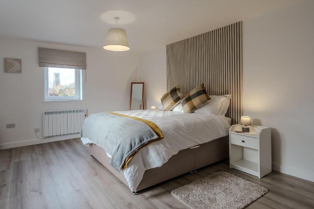 a bedroom with a large bed with a wooden headboard at Coastal apartment near Winterton beach, 2 dogs welcome in Winterton-on-Sea