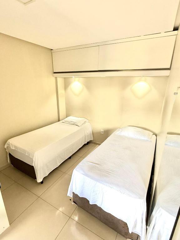 two beds in a small room with white walls at Studio Cafe duas camas de solteiro in Arapiraca