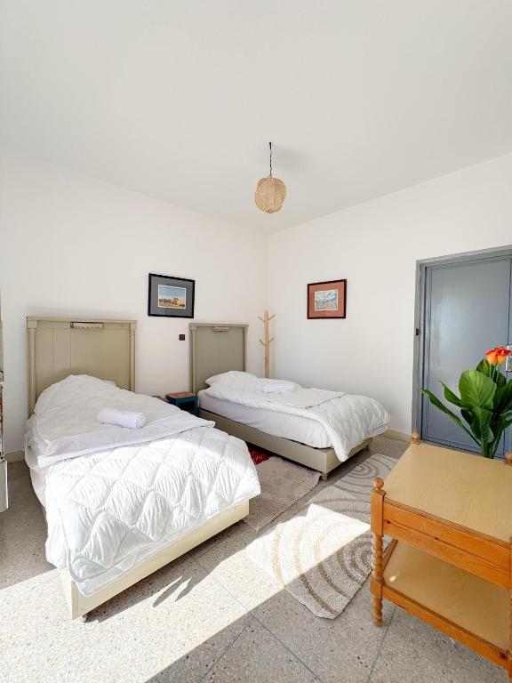 a bedroom with two beds and a table at Dar Baba Hassan - Ocean View & Ensuite in Taghazout