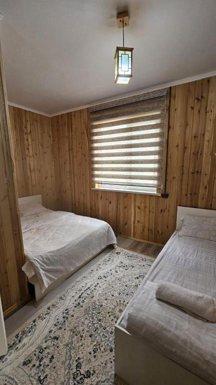 two beds in a bedroom with wooden walls and a window at Aruna Guesthouse in Saty