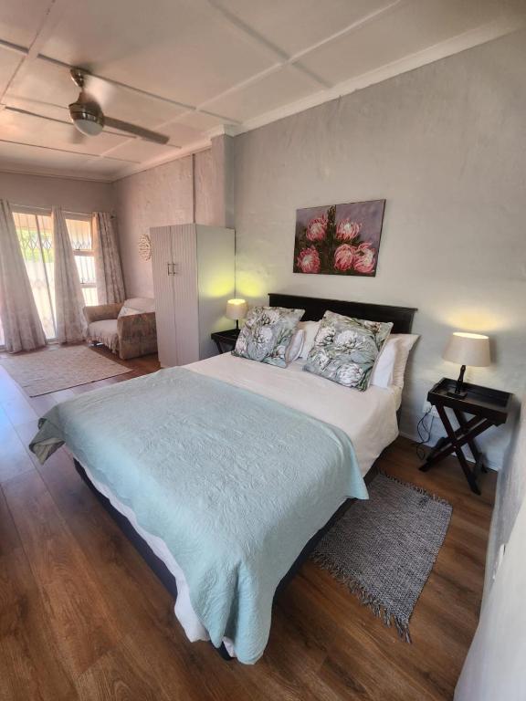 a bedroom with a large bed with a blue blanket at Cottages on Ilchester in Grahamstown