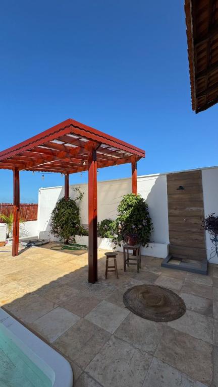 a wooden pergola next to a swimming pool at Casa Dunas Baleia in Itapipoca