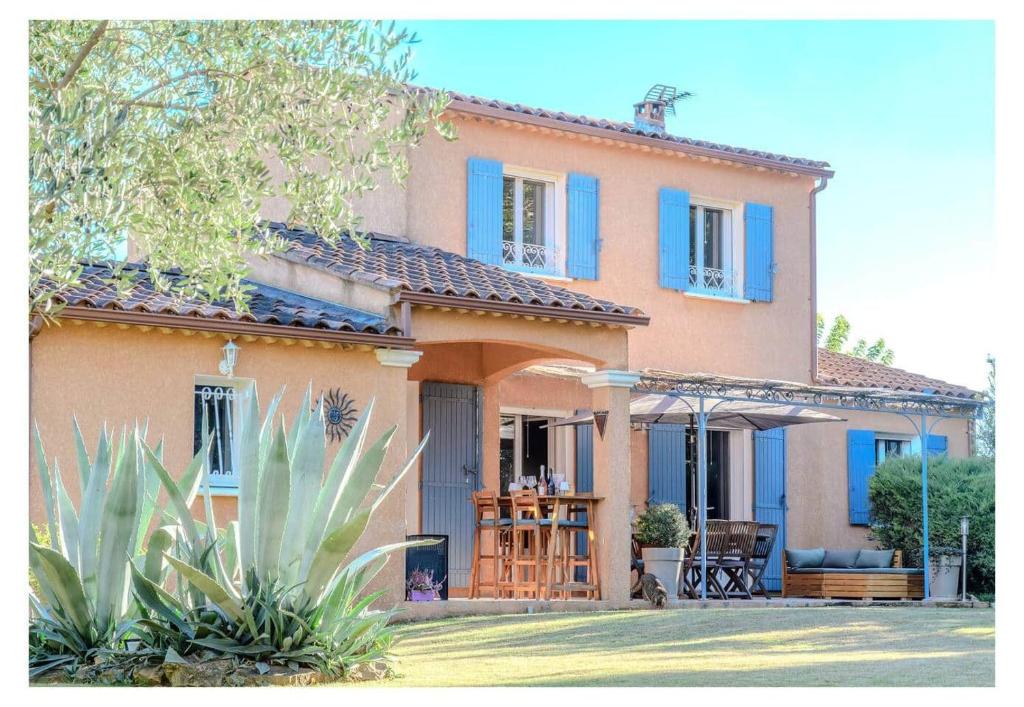 a large house with blue windows and a porch at la villa "Loane" à St Paul trois Chateaux in Saint-Paul-Trois-Châteaux