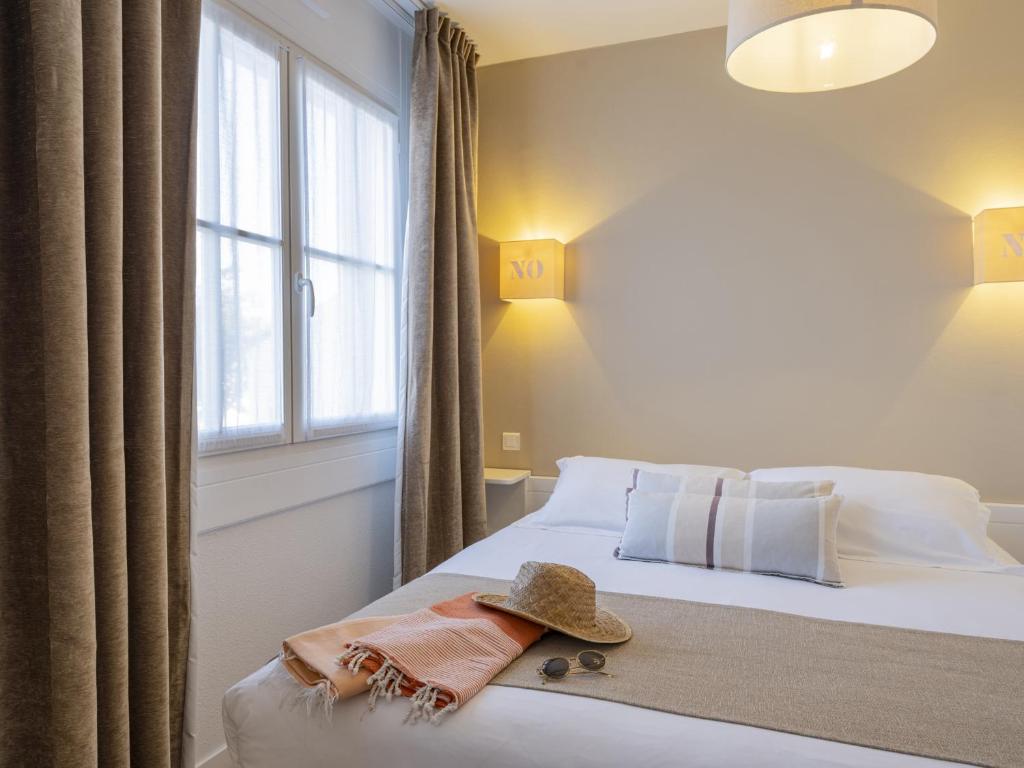 a bedroom with a bed with a hat on it at Hotel Autre Mer in Noirmoutier-en-l'lle