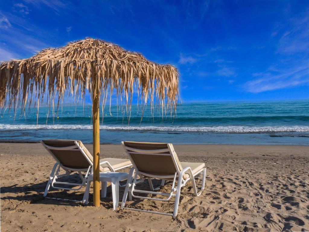 two chairs and an umbrella on the beach at Alexia Beach Hotel in Agia Marina Nea Kydonias