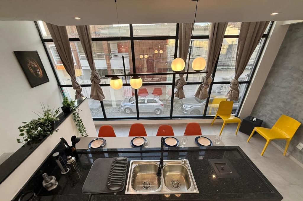 a kitchen with yellow chairs and a large window at Duplex Coité in Conceição do Coité