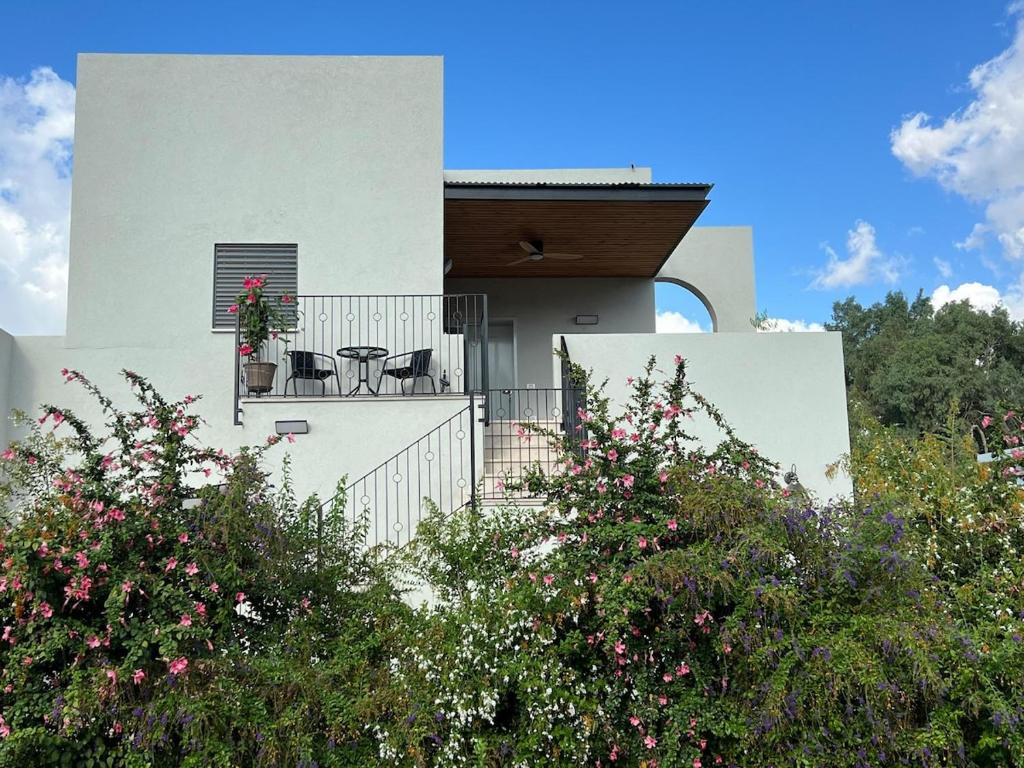 a white house with a balcony with a table and chairs at The Peleg Tal Unit - היחידה בפלג טל in Dafna