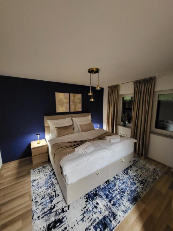 a bedroom with a large white bed and a blue wall at KRUNA Apartment in Cazin