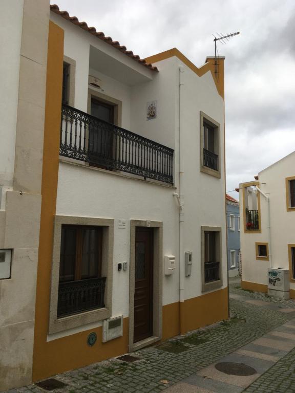 a white building with a balcony on a street at Maresia in Sines