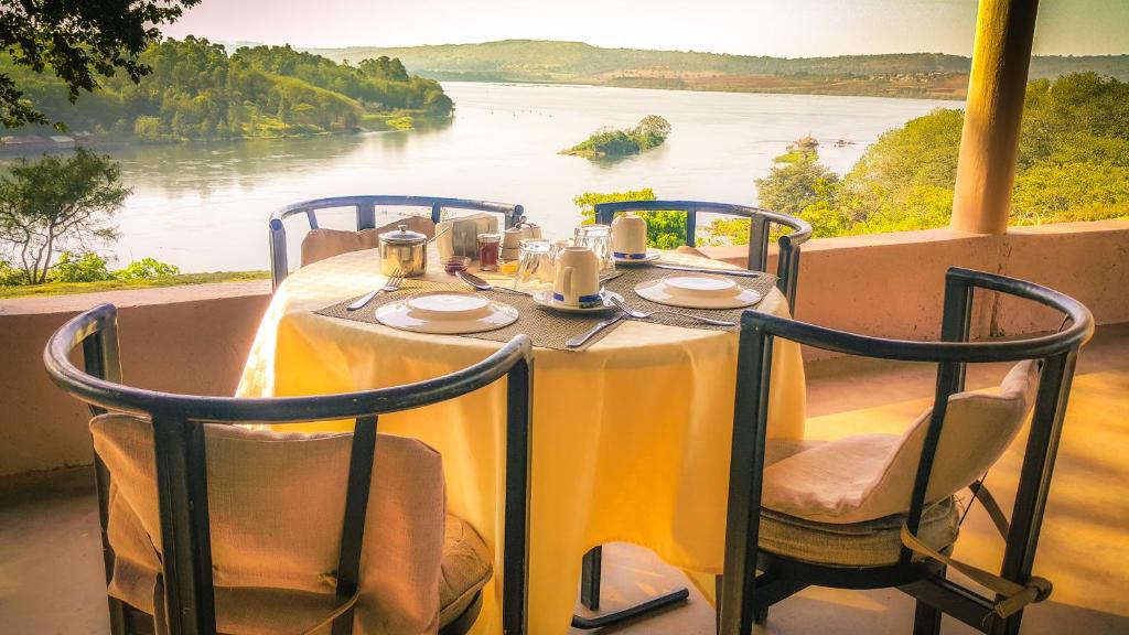 a table and chairs with a view of a river at Living Waters Resort in Jinja