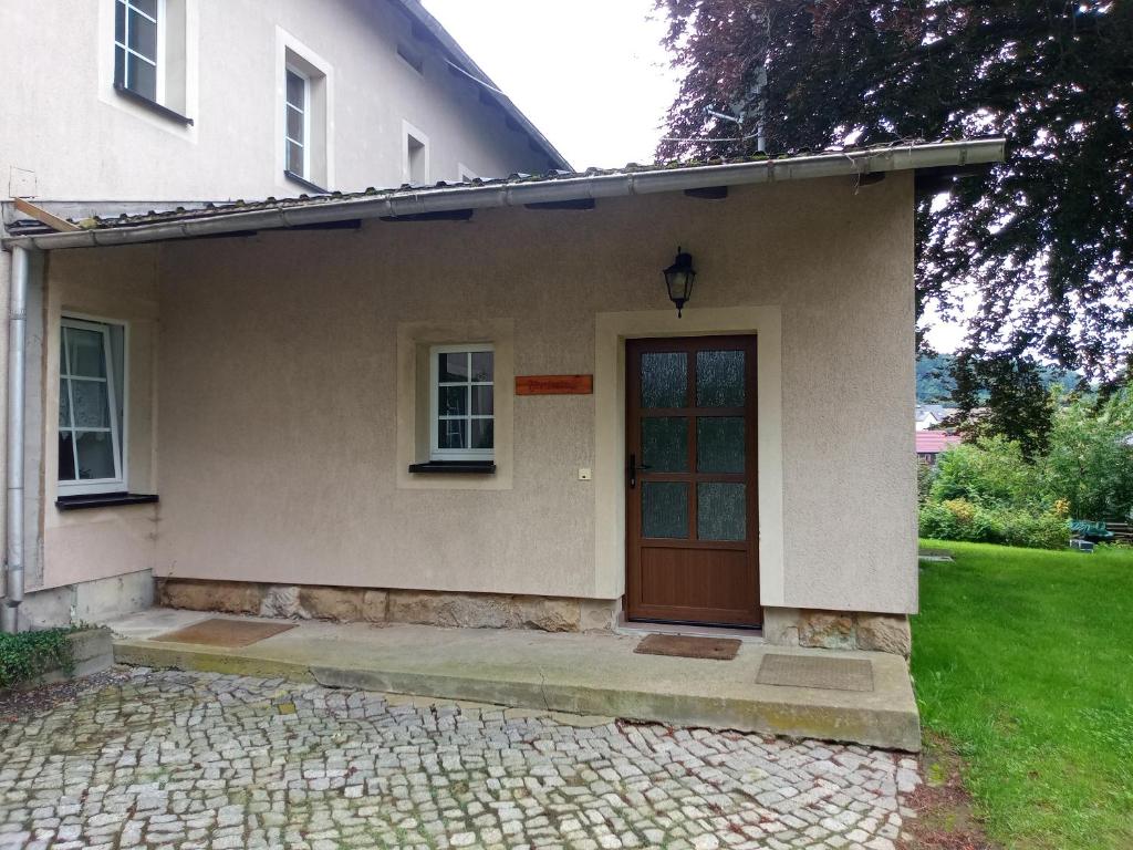 a house with a red door and a green yard at Ferienwohnung Pferdestall in Reinhardtsdorf