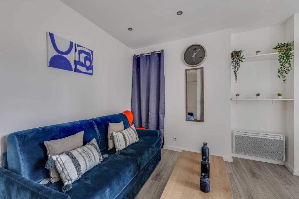 a living room with a blue couch and a clock at Cosy Studio - 2P- Clichy in Clichy