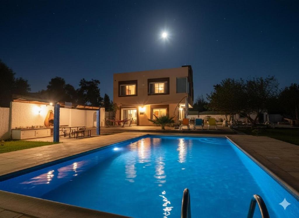 a house with a swimming pool at night at Villa Mabrouka in Raʼs al Jabal