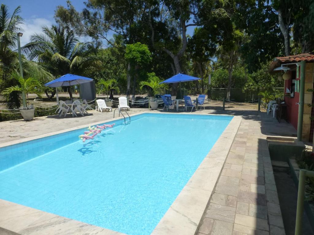 una gran piscina azul con sillas y sombrillas en Pousada das Bromélias, en Porto de Galinhas