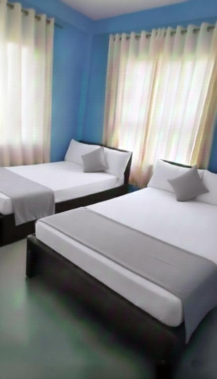two beds in a room with blue walls and windows at Daya Guest House in Pattipola