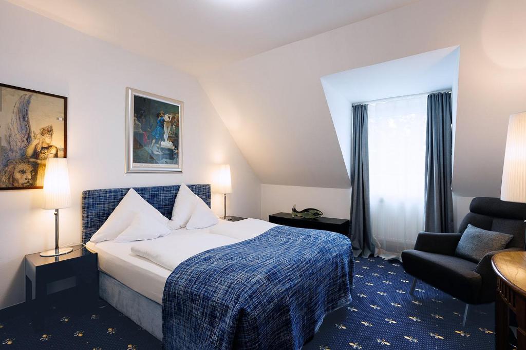 a hotel room with a bed and a chair at Hotel Nymphenburg City - München in Munich