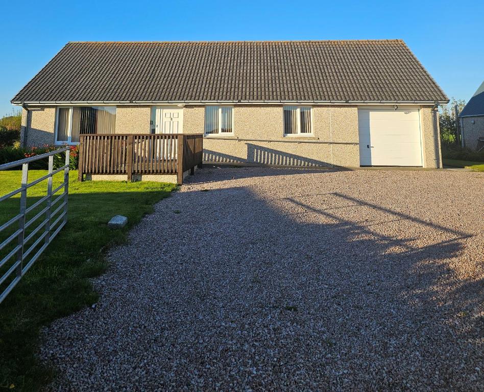 a house with a fence and a gravel driveway at Inverloch self catering in Orkney